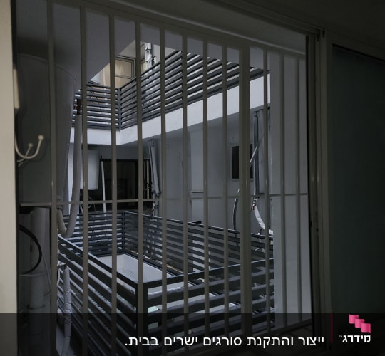 סורג ישר ממתכת בצבע לבן המותקן בפתח חלון